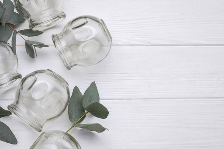 Glass cups and eucalyptus branches on white wooden table, flat lay with space for text. Cupping therapyの写真素材
