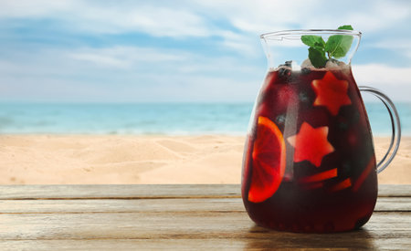Refreshing Red Sangria on wooden table near sea, space for textの写真素材