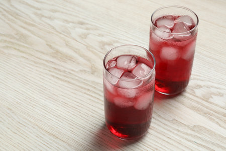 Glasses of delicious iced hibiscus tea on white wooden table, space for textの写真素材