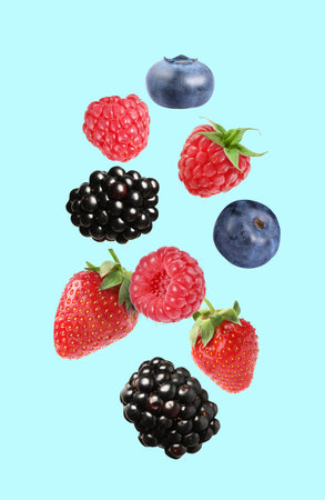 Blackberries, blueberries, strawberries and raspberries falling on light blue backgroundの写真素材