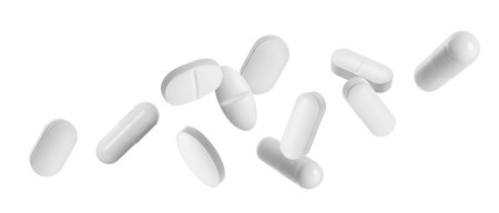 Many different pills falling on white backgroundの写真素材