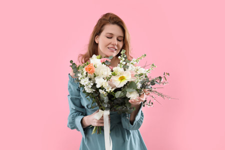 Beautiful woman with bouquet of flowers on pink backgroundの写真素材