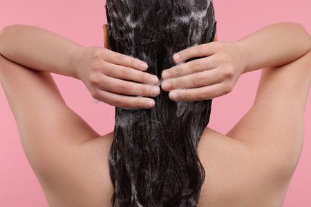 Woman washing hair on pink background, back viewの写真素材