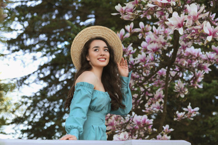 Beautiful woman near blossoming magnolia tree on spring day