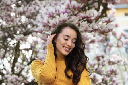Beautiful woman near blossoming magnolia tree on spring day