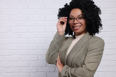 Young businesswoman in eyeglasses near white brick wall. Space for textの写真素材