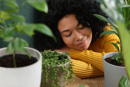 Relaxing atmosphere. Woman near potted houseplants indoorsの写真素材
