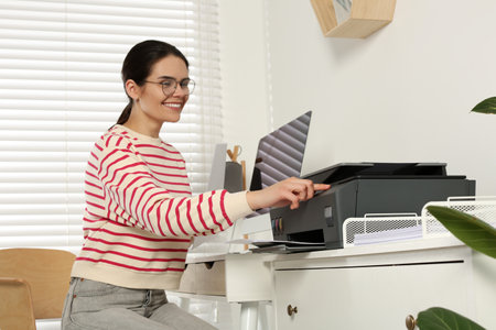 Woman using modern printer at workplace indoors