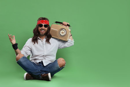 Stylish hippie man with retro radio receiver on green background, space for textの写真素材