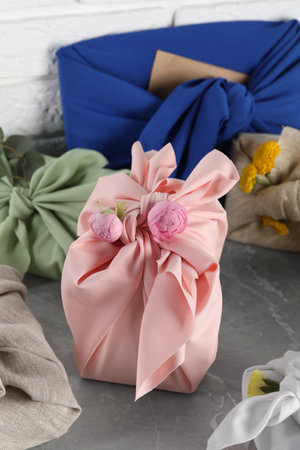 Furoshiki technique. Many gifts packed in fabric on gray tableの写真素材