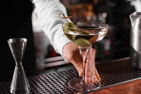 Bartender with fresh Martini cocktail at bar counter, closeupの写真素材