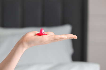 Woman holding unpacked condom on blurred background, closeup. Safe sexの写真素材
