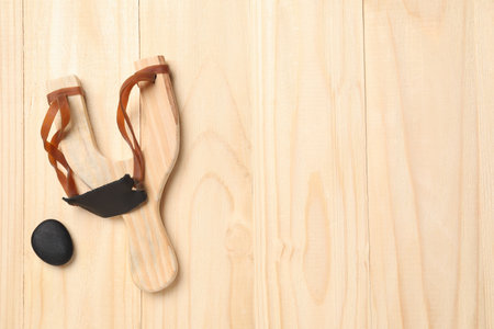 Slingshot with pebble on wooden background, top view. Space for textの写真素材