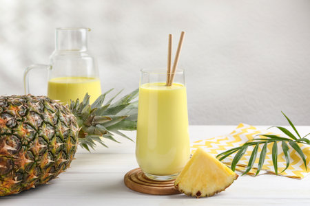 Tasty pineapple smoothie and fruit on white wooden tableの写真素材