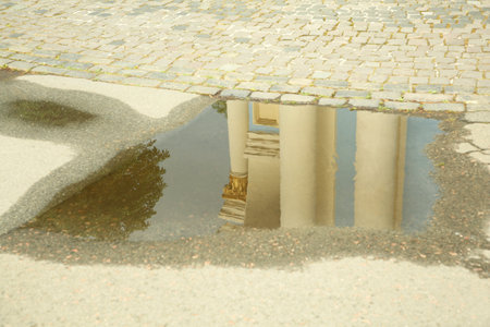 Reflection of beautiful building in puddle on asphaltの写真素材