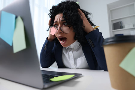 Deadline concept. Stressed woman looking at laptop and shouting in office. Many sticky notes...