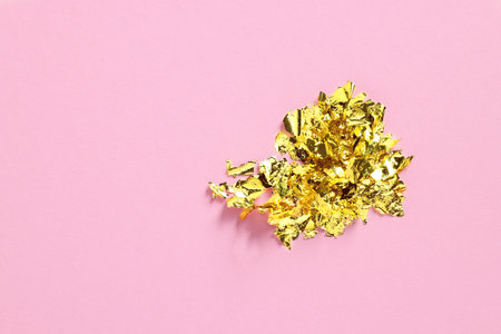 Many pieces of edible gold leaf on pink background, top view. Space for textの写真素材