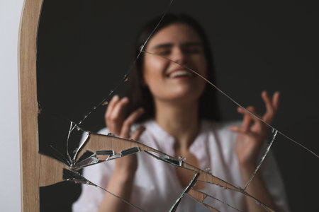 Blurred reflection of smiling woman in broken mirror