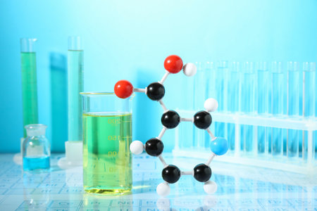 Molecular model and laboratory glassware against light blue backgroundの写真素材