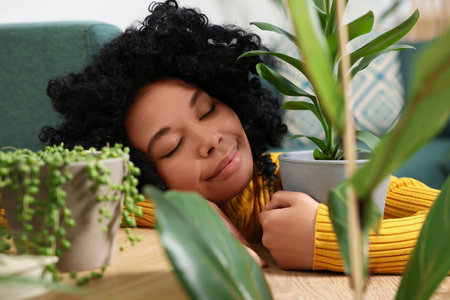 Relaxing atmosphere. Woman near potted houseplants indoorsの写真素材