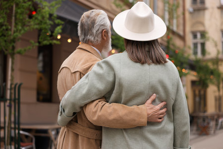 Affectionate senior couple walking outdoors, back viewの写真素材