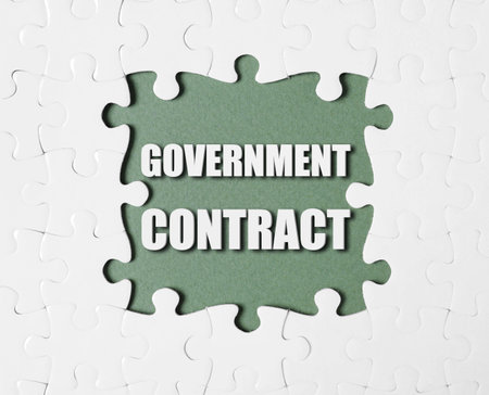 Words Government Contract surrounded by white puzzle pieces on olive color background, top viewの写真素材