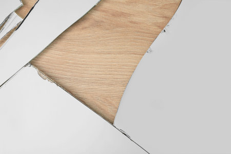 Shards of broken mirror on wooden backing board, top view
