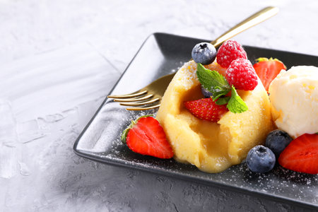 Tasty vanilla fondant with white chocolate, berries and ice cream on light gray textured table, closeupの写真素材