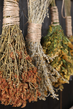 Bunches of different dry herbs hanging on wooden background, closeupの写真素材