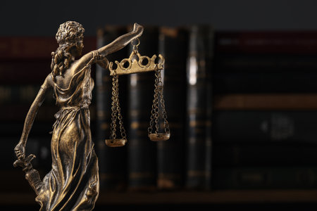 Symbol of fair treatment under law. Statue of Lady Justice near books, back view with space for text