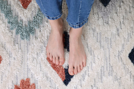 Woman on carpet with pattern at home, top viewの写真素材