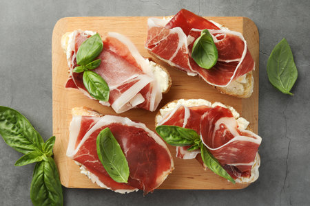Tasty sandwiches with cured ham and basil on gray table, flat layの写真素材