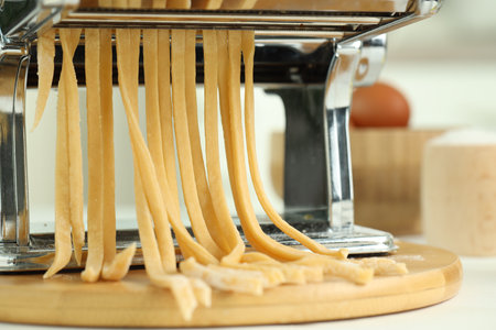 Pasta maker with raw dough on wooden table, closeupの写真素材