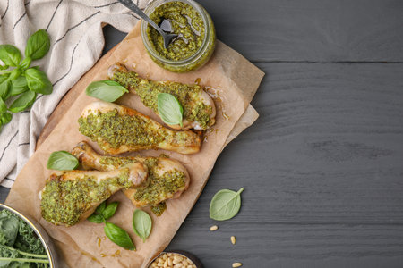 Delicious fried chicken drumsticks with pesto sauce and ingredients on gray wooden table, flat lay. Space for textの写真素材