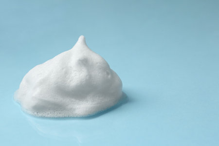 Foam on light blue background, space for text. Face cleanser, skin care cosmeticの写真素材