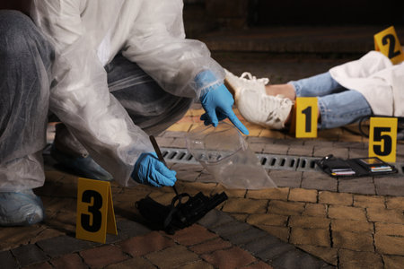 Criminologist in protective gloves working at crime scene with dead body outdoors, closeupの写真素材