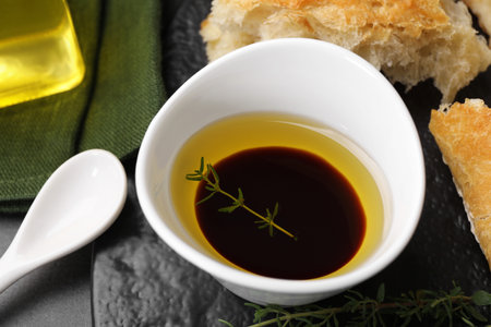 Bowl of organic balsamic vinegar with oil, thyme and bread on gray table, closeupの写真素材