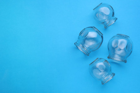 Glass cups on light blue background, flat lay and space for text. Cupping therapy