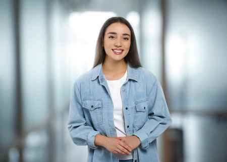 Portrait of happy woman in office. Pretty girl looking at camera and smiling on blurred backgroundの写真素材