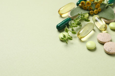 Different pills and herbs on light green background, space for text. Dietary supplementsの写真素材