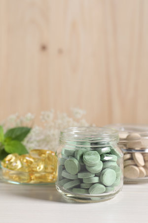 Jars with different pills on white wooden table, space for text. Dietary supplementsの写真素材