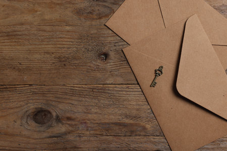 Paper envelopes and small key on wooden table, flat lay. Space for textの写真素材