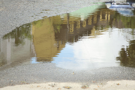 Reflection of buildings in rippled puddle water on asphaltの写真素材