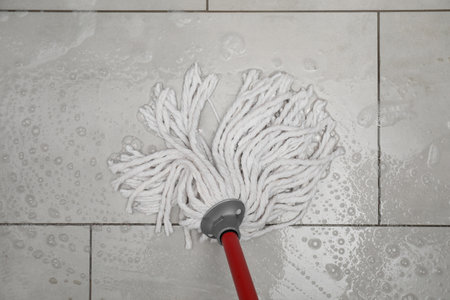 Cleaning gray tiled floor with string mop, top viewの写真素材