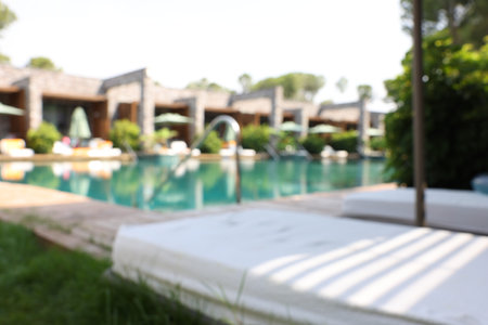 Sun loungers near outdoor swimming pool, blurred view. Luxury resortの写真素材