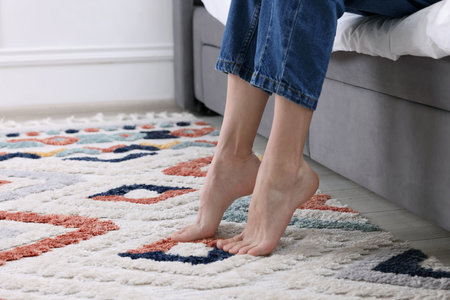 Woman on carpet with pattern at home, closeup. Space for textの写真素材