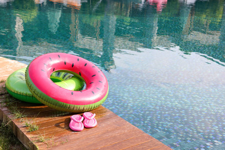 Inflatable rings and flip flops on wooden deck near swimming pool. Luxury resortの写真素材