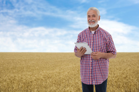 Farmer with tablet computer in field. Harvesting seasonの写真素材