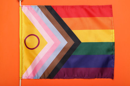 Bright progress flag on orange background, top view. LGBT pride