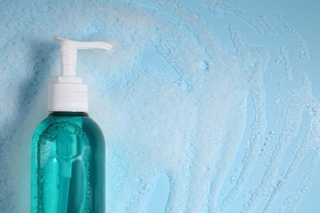 Bottle of cosmetic product and foam on light blue background, top view. Space for textの写真素材